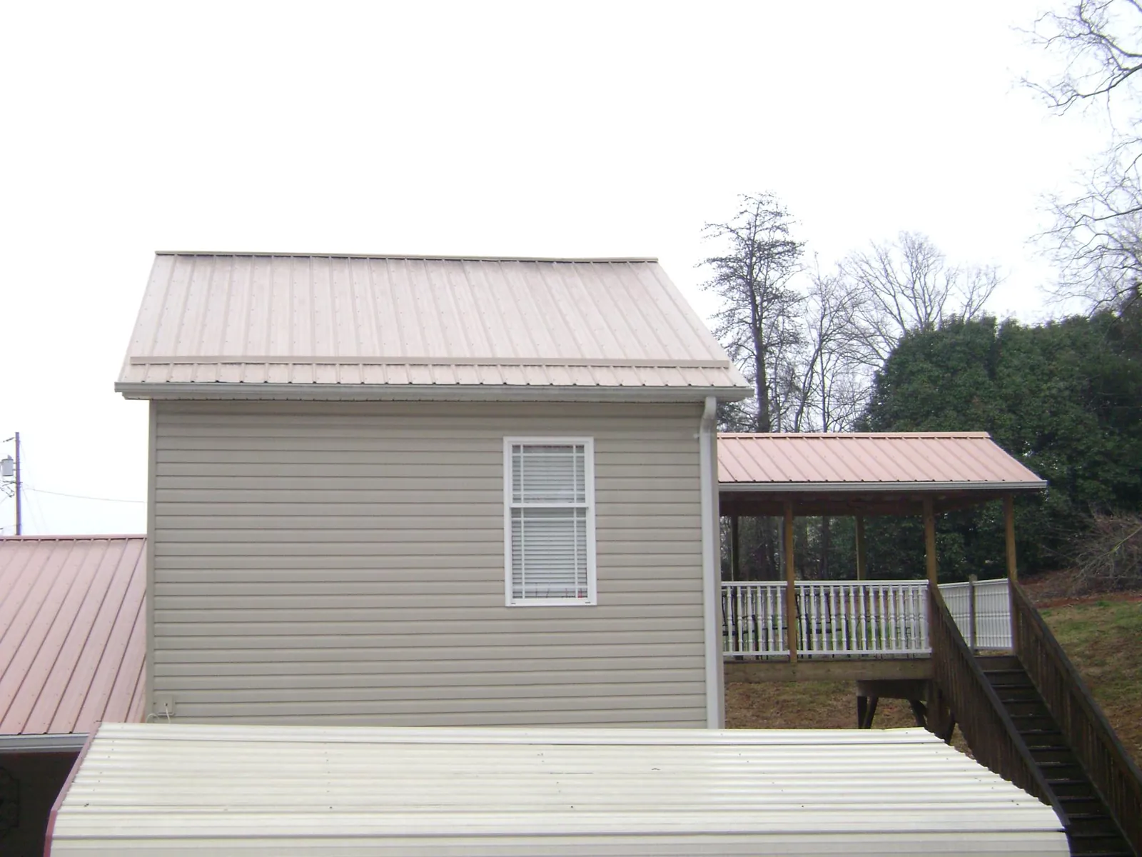 Tan metal roofs on a two story addition and attached porch, from a Roof Replacement job in Minturn